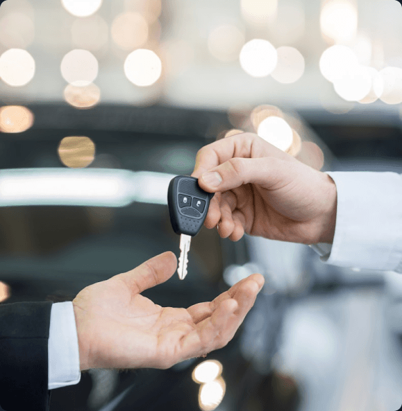 A salesperson handing car keys to a customer
